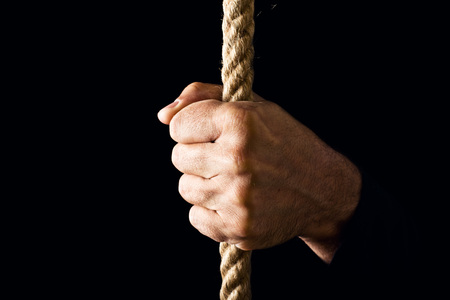 Hand holding a rope, strength and determination concept.