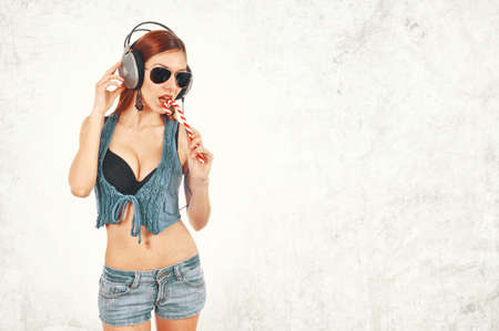 Pretty young redhead woman eating lollipopの写真素材