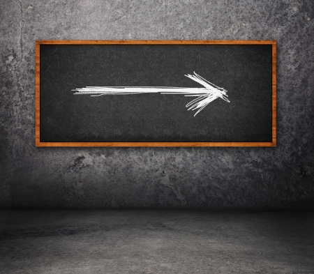 Direction arrow on blackboard in concrete roomの写真素材