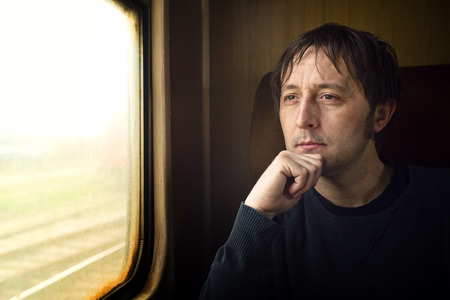 Traveling by train. Man traveling by train, looking through the dirty window.