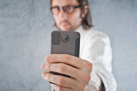 Businessman taking picture with mobile phone, selective focus on device and hand