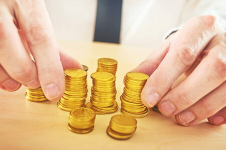 Businessman is stacking golden coinsの写真素材