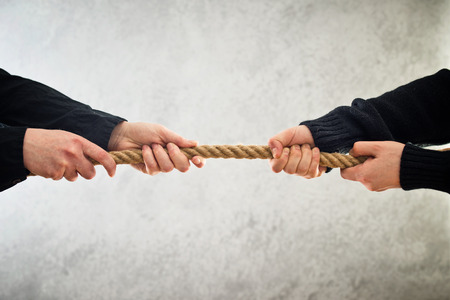 female hands pulling rope to opposite sidesの写真素材