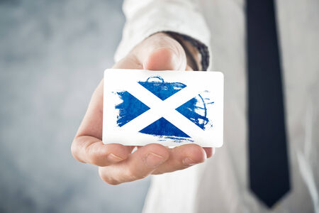 Scotish Businessman holding business card with Scotland Flag  International cooperation, investments, business opportunities concept の写真素材