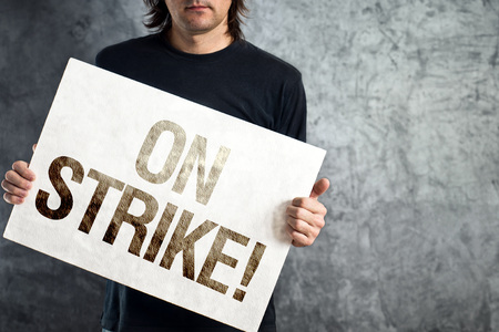 Man holding banner with ON STRIKE printed protest message 