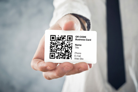 Businessman holding QR code business card with personal data. Modern technology concept.の写真素材