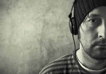 Casual unshaven man with black headphones is listening to music