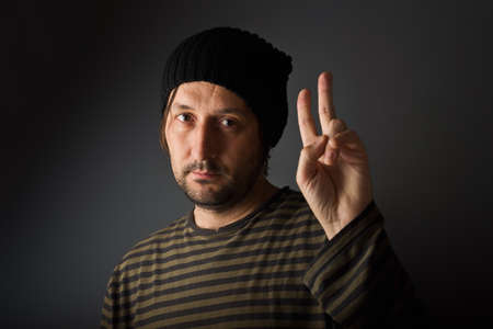 Casual caucasian man giving two fingers as peace or victory symbolの写真素材