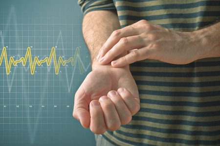 Man checking his pulse by pressing the wrist with fingers. Health issues concept.の写真素材