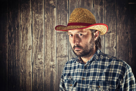 Farmer with cowboy straw hat in front of wooden byre wallの写真素材