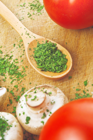 Chopped parsley on wooden spoon in the kitchen. Food preparation background.の写真素材