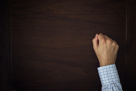 Male hand is knocking on wooden doorの写真素材