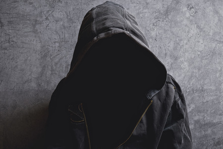 Faceless unknown and unrecognizable man withouth identity wearing hood in dark room, spooky criminal person.の写真素材