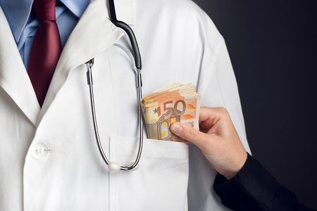 Corruption in Health Care Industry, Doctor receivening large amount of Euro banknotes as a bribe.の写真素材