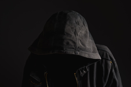 Faceless unknown and unrecognizable man without identity wearing hood in dark room, spooky criminal person.の写真素材