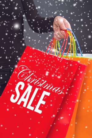 Woman holding red Christmas Sale Shopping Bag. Consumerism and Seasonal Shopping concept.の写真素材