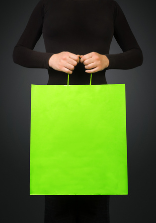 Woman holding green shopping bag for discount prices seasonal purchasing event. Saleout and clearance sale concept.の写真素材