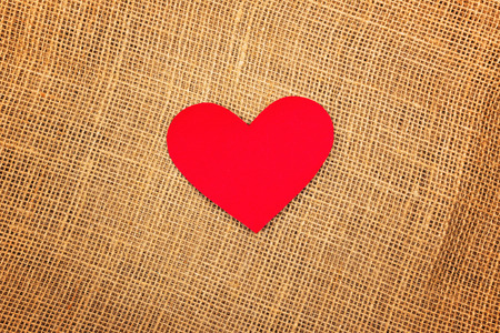 Valentine's Day background with red paper hearts on natural jute burlap texture as copy space.の写真素材
