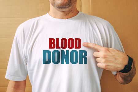 Proud volunteer blood donor wearing white t-shirt, male person posing at cameraの写真素材