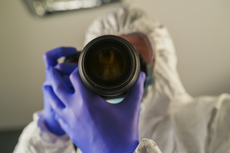 Crime scene forensics investigator with digital camera taking pictures as evidence for the investigationの写真素材