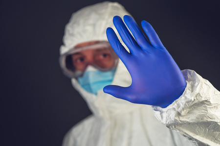 Medical scientist wearing protective clothing and glassware gesturing stop sign in quarantineの写真素材