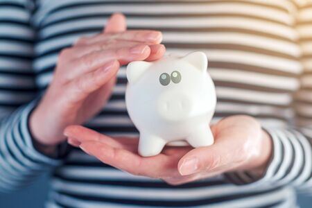 Woman cuddles piggy coin bank, responsible home budgeting and money savingの写真素材
