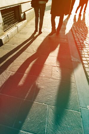 Long shadows of pedestrian people on the street pavement in winter afternoon