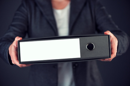 Businesswoman holding document ring binder with blank label as copy space, female accountant or financial advisor archiving business documentationの写真素材