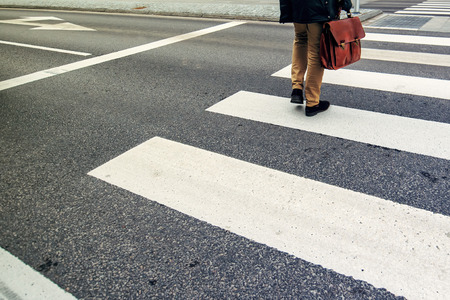 Unrecognizable businessman walking over pedestrian zebra crossing on his way to workの写真素材
