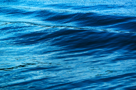 Sea waves formed from sailing ship, abstract dark blue background