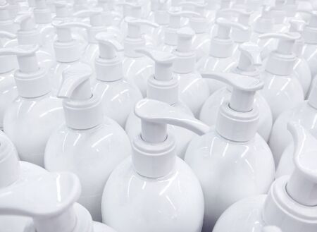 White unlabeled liquid soap bottles in supermarket, repeating pattern of large group of plastic...