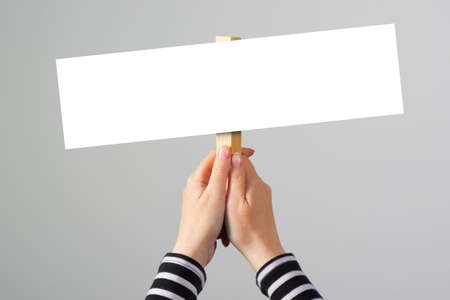 Female hand holding blank mock up banner sign as copy space for quotation text or graphic design