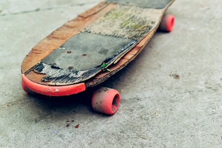 Old weathered skateboard on concrete surface, abandoned in skate park, selective focusの写真素材