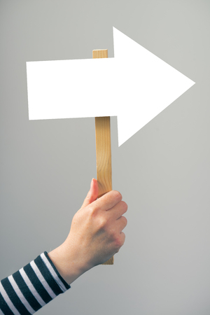 Woman holding guiding direction arrow sign in hand, concept of guidance and decision makingの写真素材