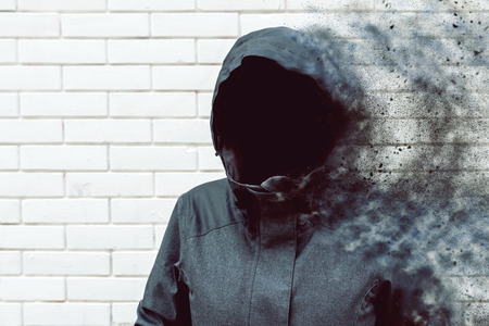 Thinking mind blowing thoughts, faceless hooded person against white brick wallの写真素材