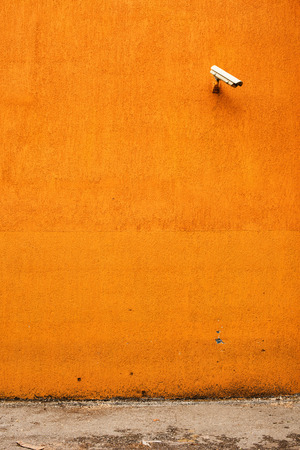 CCTV camera on orange building facade as copy space