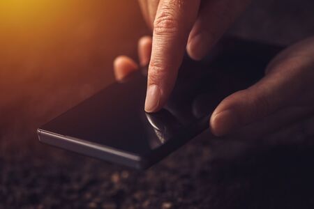 Close up of hands using mobile phone, selective focus on finger pushing touch screenの写真素材