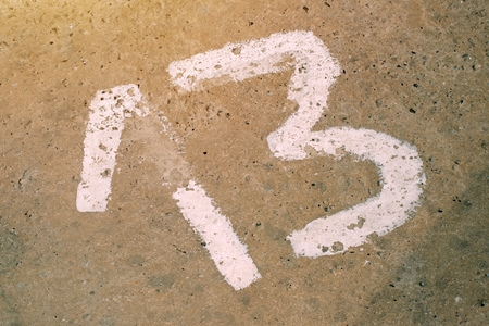 Number thirteen on the concrete floor, sign on empty private parking lot, 13 is considered to be unlucky number in many countriesの写真素材