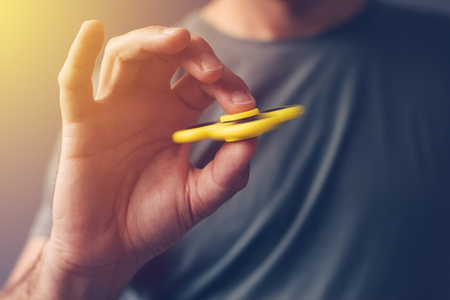 Adult man playing with fidget spinner toy, selective focusの写真素材