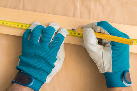 Carpenter handyman using pencil to mark the plank on the woodwork workshop tableの写真素材