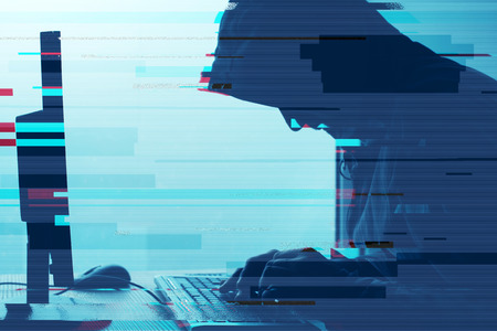 Hooded computer hacker working on desktop PC computer. P2P and piracy, computer virus and trojans,...