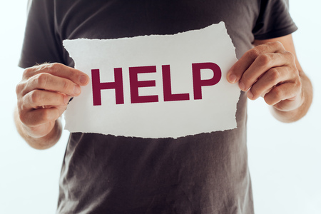 Man asking for help and support. Adult caucasian male holding paper sign with HELP word printed.の写真素材
