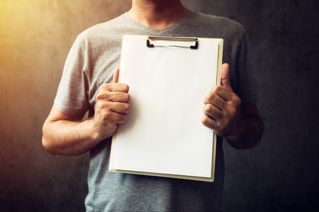 Casual caucasian adult man holding blank notepad paper as copy spaceの写真素材