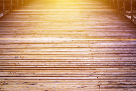 Sunset sunlight on wooden pier boardwalk at the seaside as vanishing perspective background with selective focusの写真素材