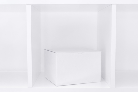 White cardboard box on wooden shelf as copy space useful for package design mock up or postal mail and package delivery service backgroundの写真素材