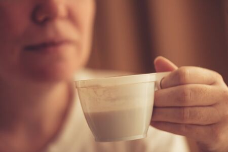 Woman drinking coffee from plastic cup in the morningの写真素材