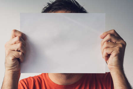 Man hiding behind blank white paper as copy space for text messageの写真素材