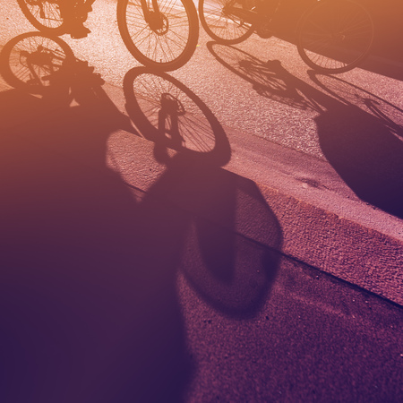 Cyclist riding bicycle on the road through city street in urban surrounding