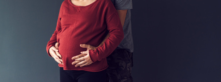 Soldier hugging his pregnant wife, couple expecting babyの写真素材