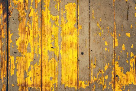 Yellow weather worn wooden texture with paint peeling off the surface, rustic and aged background and patternsの写真素材